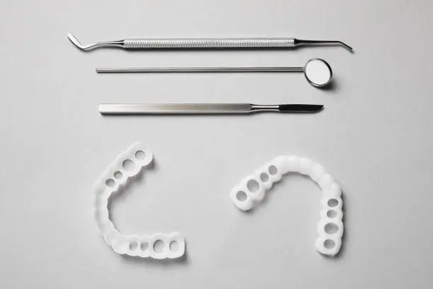 Bite correction. Mouth guards and dentist tools on light grey background, flat lay