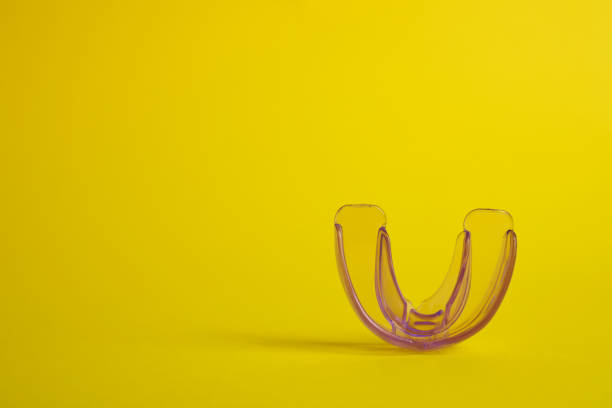 Transparent dental mouth guard on yellow background, space for text. Bite correction