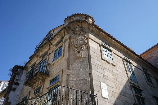 'Pazo de Fondevila', typical palatial architecture of the Compostela baroque. The decoration focuses on the chamfered corner of the building, where we can see an ostentatious shield beneath a circular pediment 
Santiago de Compostela, Galicia, Spain 10092023