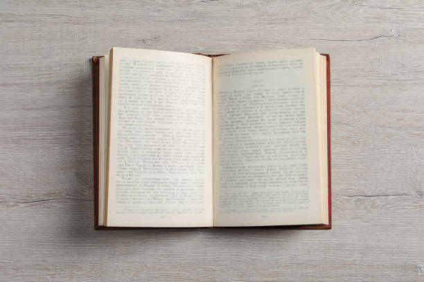 Open hardcover book on white wooden table, top view