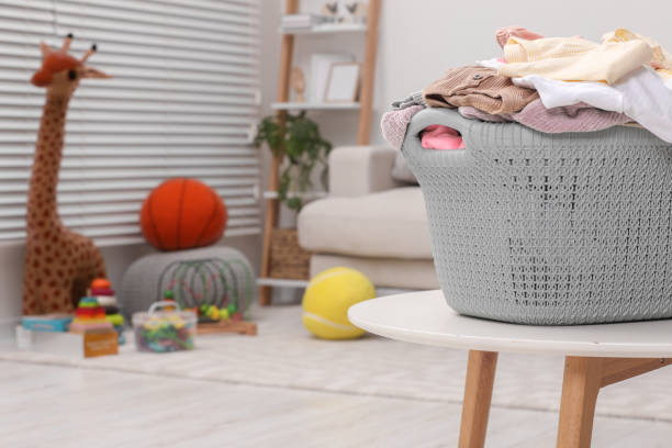 istock Laundry basket with baby clothes on white table in room. Space for text 1804450328