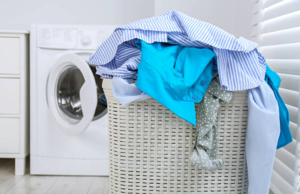 istock Plastic laundry basket overfilled with clothes in bathroom, closeup 1804451418