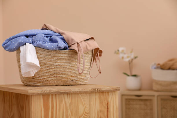 istock Wicker laundry basket overfilled with clothes on wooden table indoors. Space for text 1804451927