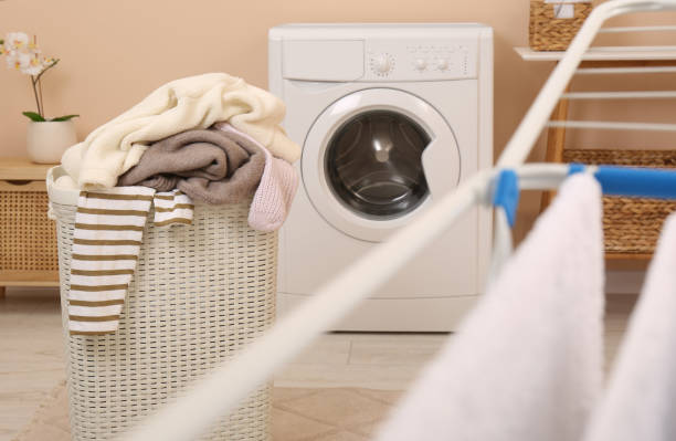 istock Laundry basket overfilled with clothes near washing machine in bathroom 1804453638