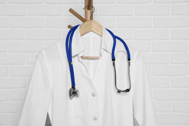 istock Medical uniform and stethoscope hanging on rack near white brick wall 1804454245