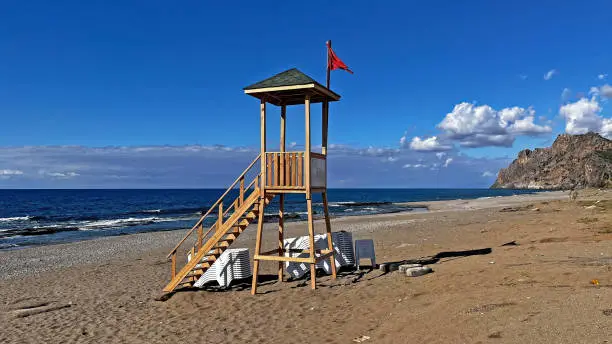 Photo of Lifeguard tower on the beach in the fall. Blue sky and clouds. Gazipasa castle.