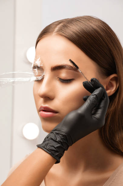 el maquillador hace un estilo duradero de las cejas y coloreará las cejas. laminación de cejas. maquillaje profesional y cuidado facial. - coloreado a mano fotografías e imágenes de stock