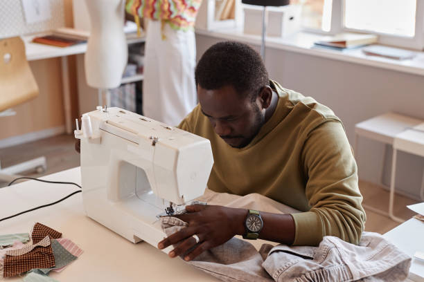 istock Young African American couturier using electric sewing machine 1804532881