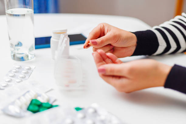 istock Woman hand putting pills into open pill organizer or plastic pillbox 1804542829