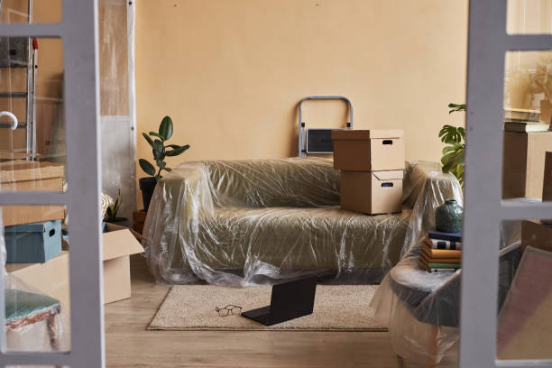 istock Laptop standing on carpet next to couch covered with cellophane 1804551599