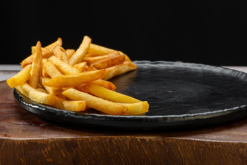 Portion of french fries in a holder on rustic wooden table.