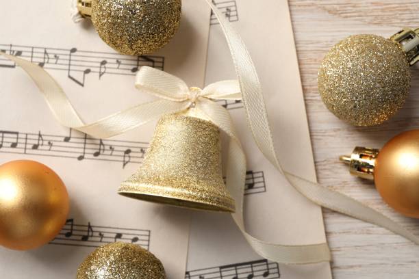 campana dorata lucida con fiocco, spartiti musicali e palline decorative su tavolo in legno, flat lay. decorazione natalizia - bell jingle christmas music foto e immagini stock