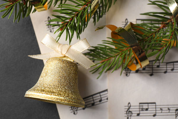 흰색 리본, 전나무 가지, 회색 테이블에 음악 시트가 있는 황금빛 반짝이는 종, 평면도. 크리스마스 장식 - bell jingle christmas music 뉴스 사진 이미지