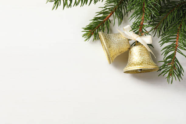 istock Christmas bells and fir tree branches on white wooden table, flat lay. Space for text 1804555423