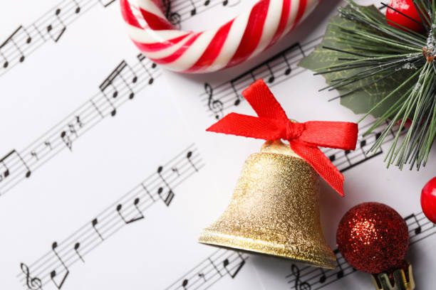 istock Golden shiny bell with red bow and Christmas decor on music sheets, flat lay 1804555937