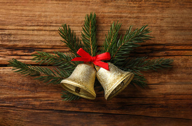 istock Christmas bells and fir tree branches on wooden table, flat lay 1804555952