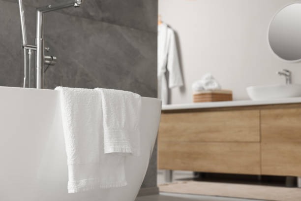 istock Fresh white towels on tub in bathroom. Space for text 1804557031