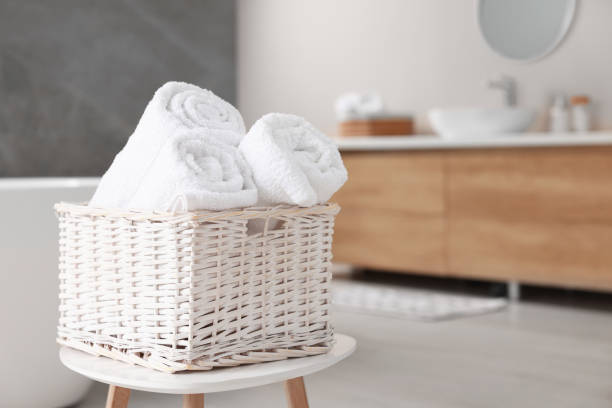 istock Wicker basket with fresh white towels on stool in bathroom. Space for text 1804557714