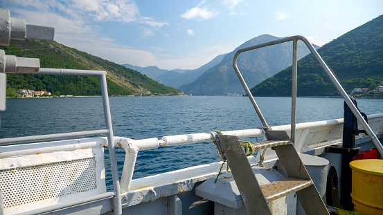 View from the old ferry boat on calm sea waves and high mountains in Kotor bay, Montenegro.