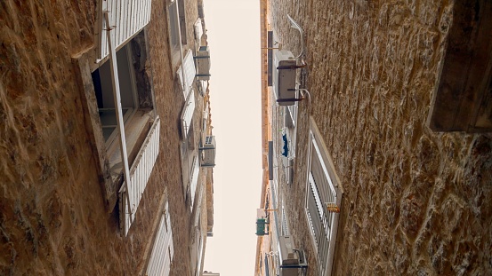 Narrow street with ancient stone buildings with wooden window blinds and red tile roofs at European old town.