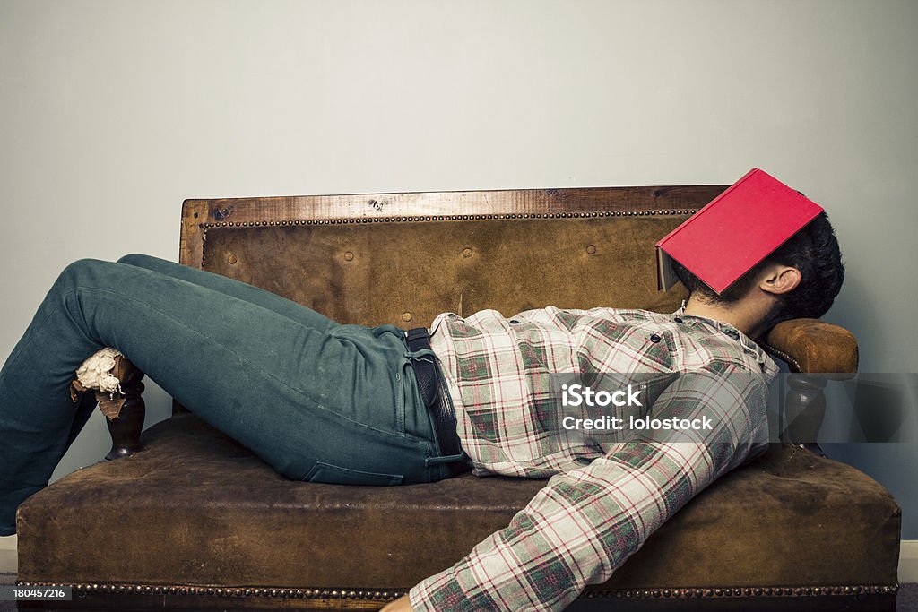 Homem dormindo no sofá velho com livro com seu rosto - Foto de stock de Dormindo royalty-free