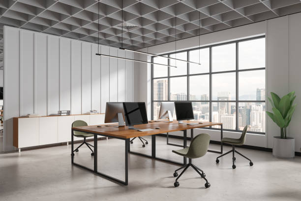 istock White coworking interior with pc monitors and sideboard, panoramic window 1804583627