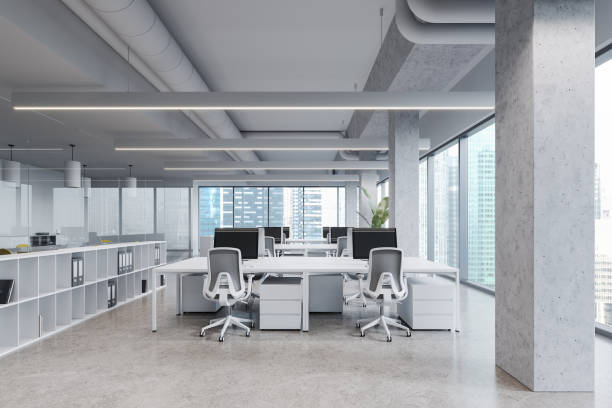 istock White stylish office interior with pc monitors and shelf, panoramic window 1804584186