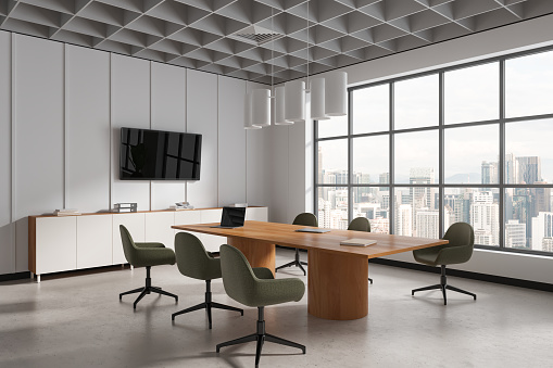 Interior of modern meeting room with white walls, concrete floor, long conference table with green chairs, panoramic window and big TV display on the wall. 3d rendering