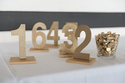Three gold metal table number signs arranged on a white surface