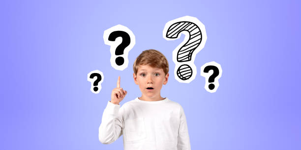 istock Impressed boy with finger point up at question marks on blue background 1804594662