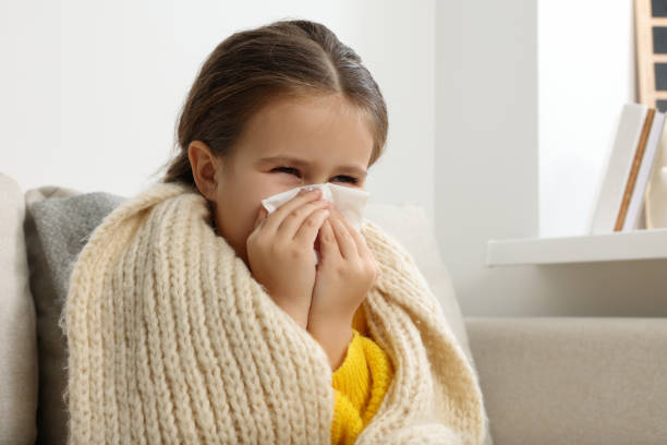 istock Girl blowing nose in tissue on sofa in room. Cold symptoms 1804601320