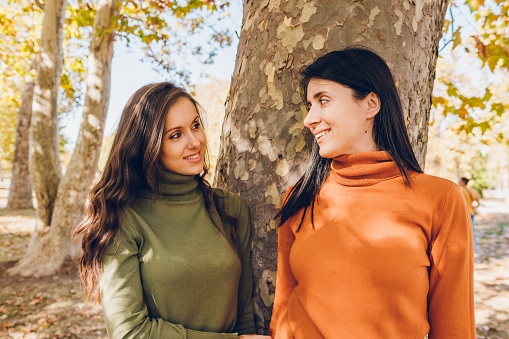 Two young woman enjoys in the park in autumn.