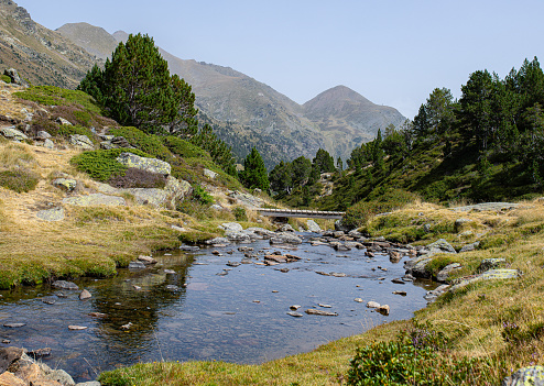 Coma del Forat river with wooden bridge in the background next to the mountains of Andorra