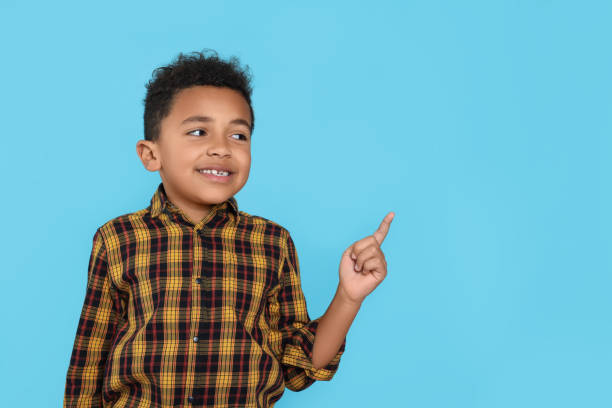 istock Cute African-American boy pointing on turquoise background. Space for text 1804621668
