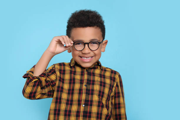 istock Cute African-American boy with glasses on turquoise background 1804622250
