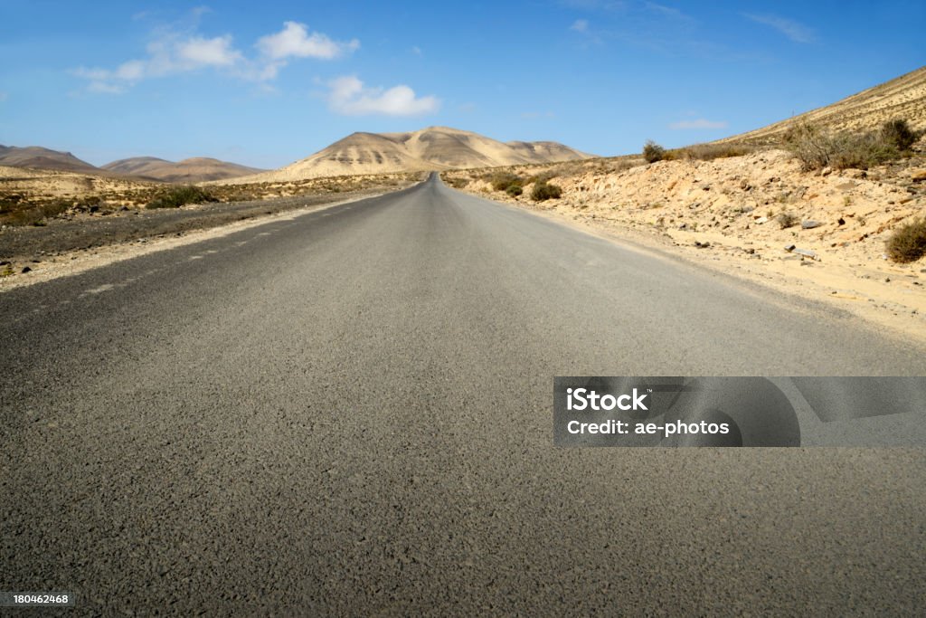 Асфальтовая дорога и Вулканический пейзаж на fuerteventura под голубое небо - Стоковые фото Асфальт роялти-фри