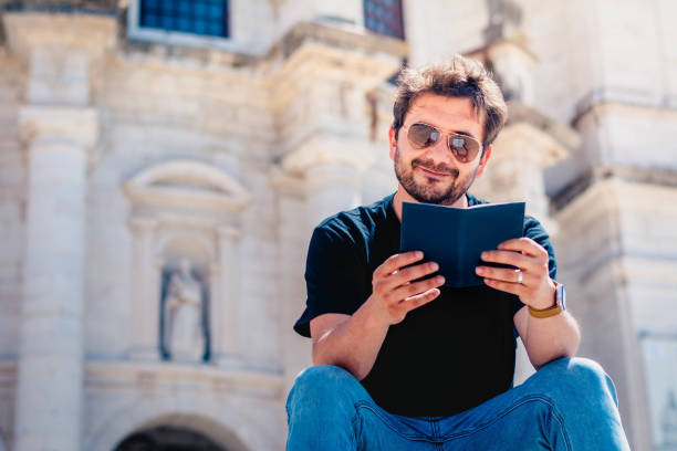 istock Young man reading a book in the street 1804634984