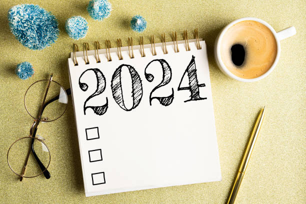 istock 2024 New year resolutions on desk. 2024 goals list with notebook, coffee cup, festive decorations on golden background. Resolutions, plan, goals, checklist, idea concept. New Year 2024 resolutions. Copy space 1804654739