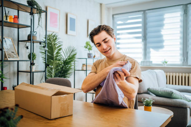 istock Young man unpacking clothes after online shopping 1804664238