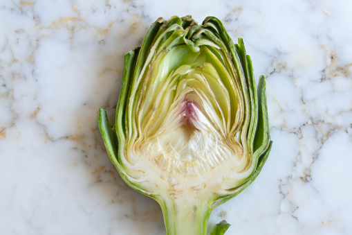Cross section of a baby artichoke on a marble table top