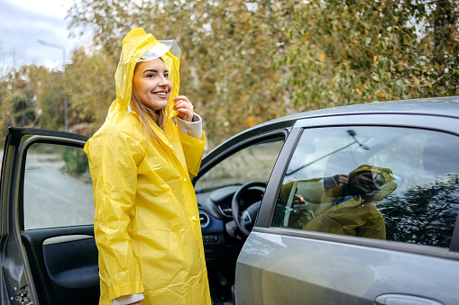 Young woman leaving from work on rainy day using her car
