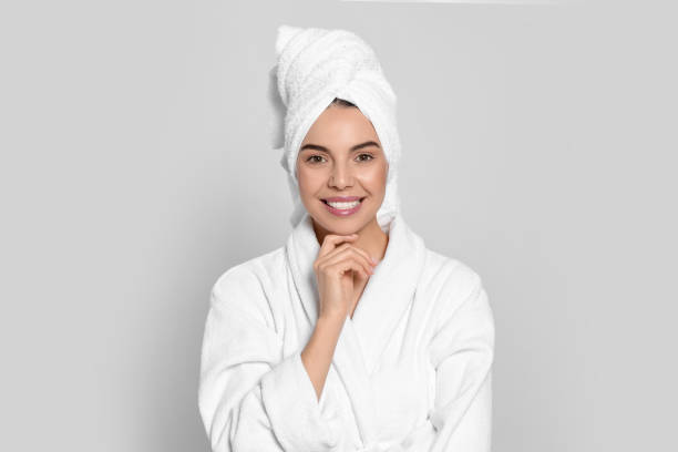 istock Young woman in bathrobe with towel on light grey background. Spa treatment 1804668756