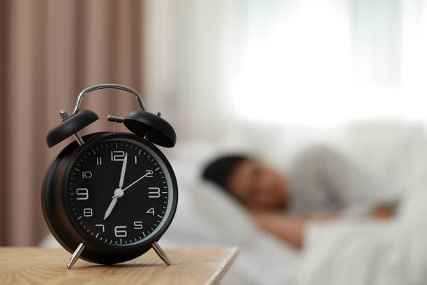 istock Woman sleeping in bedroom, focus on alarm clock. Space for text 1804678056