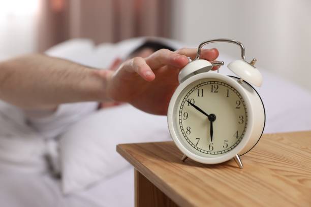istock Man turning off alarm clock in bedroom, focus on hand 1804678057