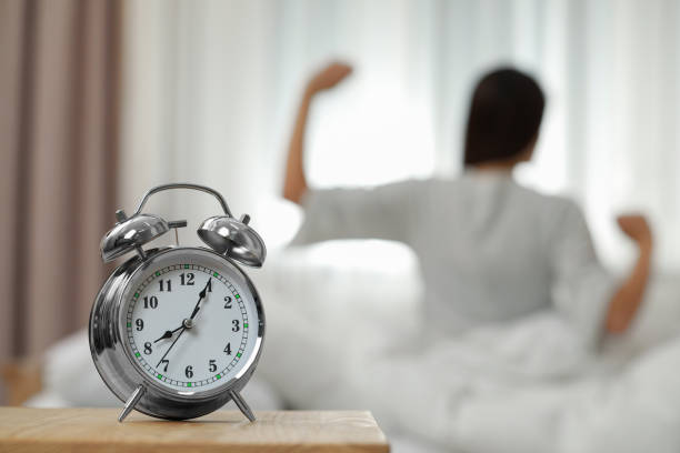 istock Woman stretching in bedroom, focus on alarm clock. Space for text 1804679526