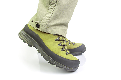 Trekking boots for hiking on the legs of a tourist on a white background. Equipment for travel and hiking