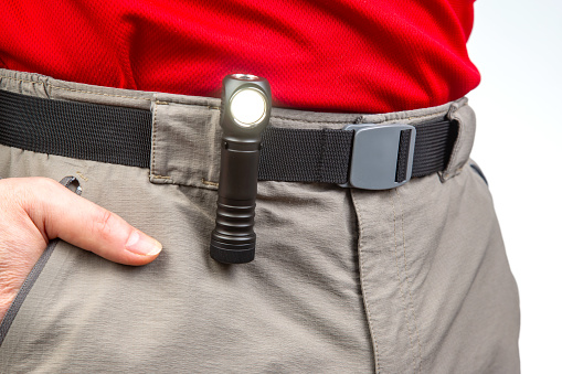 flashlight with clips on the waistband of trekking trousers. EDC items