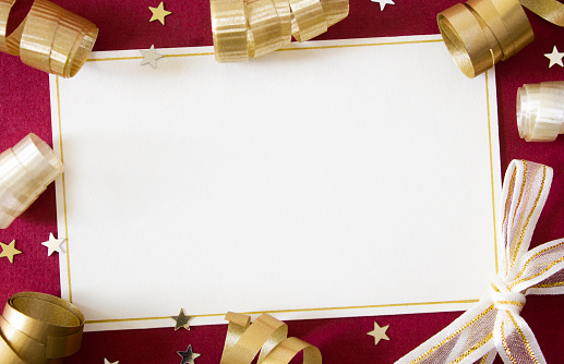 A blank card with white copy space, surrounded with gold ribbons on a red background.