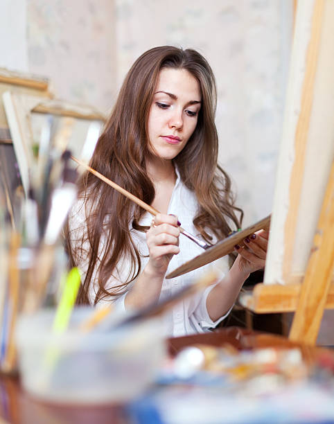 istock Long-haired artist paints on canvas 180476022