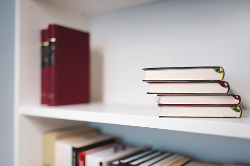 Two stacks of books on a white bookshelf.